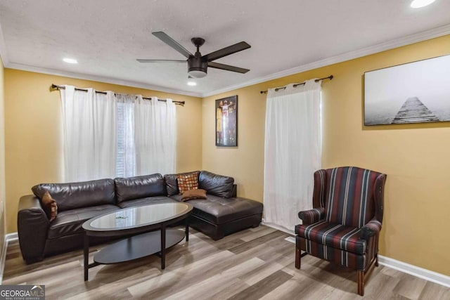 living area featuring a ceiling fan, wood finished floors, baseboards, recessed lighting, and crown molding