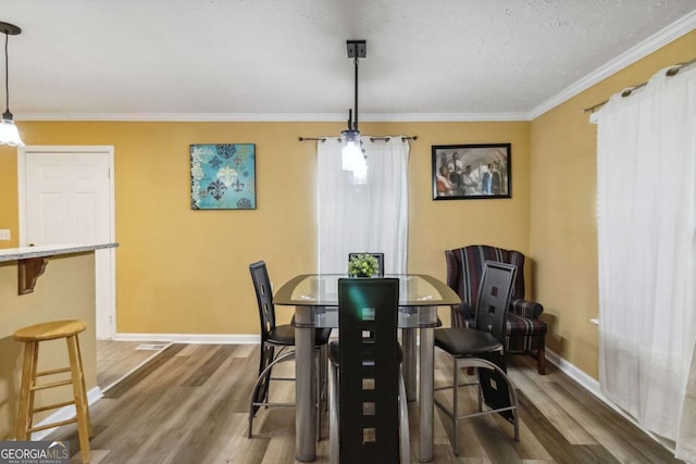 dining area with crown molding, wood finished floors, and baseboards