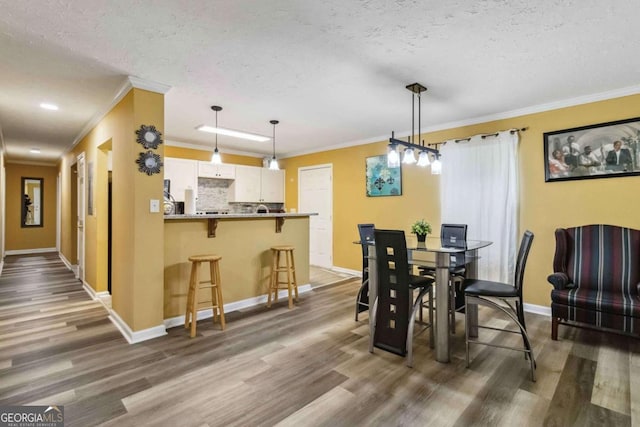 dining space featuring crown molding, a textured ceiling, dark wood-type flooring, and baseboards