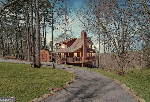 view of front of house featuring a chimney, an outdoor structure, a front yard, and a shed