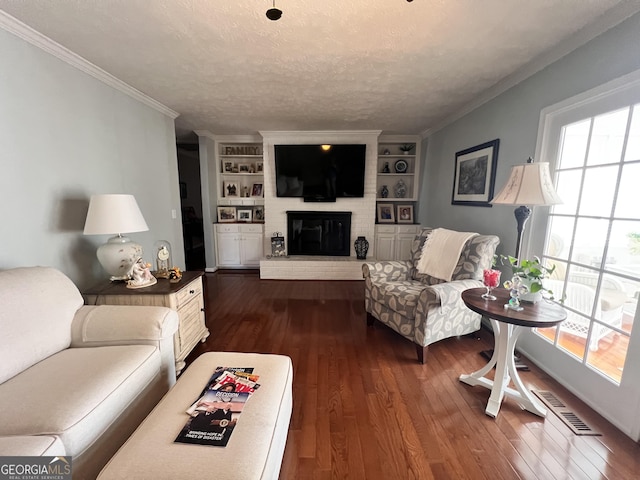 living area with dark wood finished floors, crown molding, a brick fireplace, and a textured ceiling