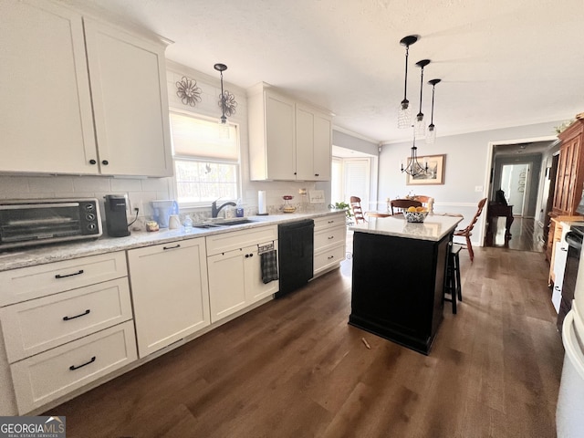 kitchen featuring decorative light fixtures, a toaster, dishwasher, dark wood-style floors, and a sink