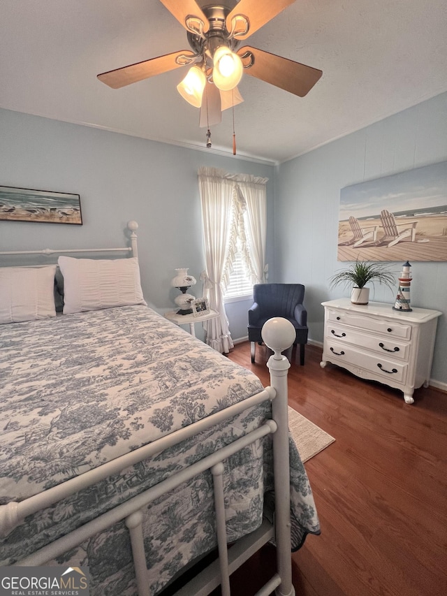 bedroom featuring baseboards, wood finished floors, and a ceiling fan