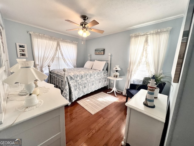 bedroom with multiple windows, dark wood-type flooring, ceiling fan, and crown molding