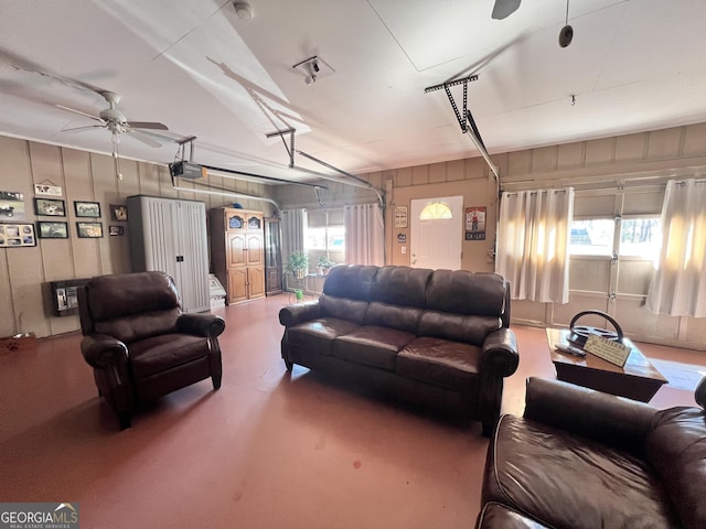 living room featuring finished concrete flooring, a garage, and ceiling fan