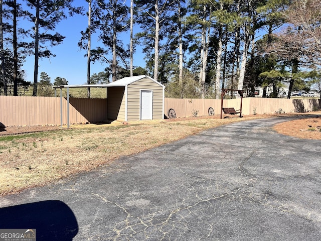 view of yard featuring a storage unit, an outbuilding, and fence