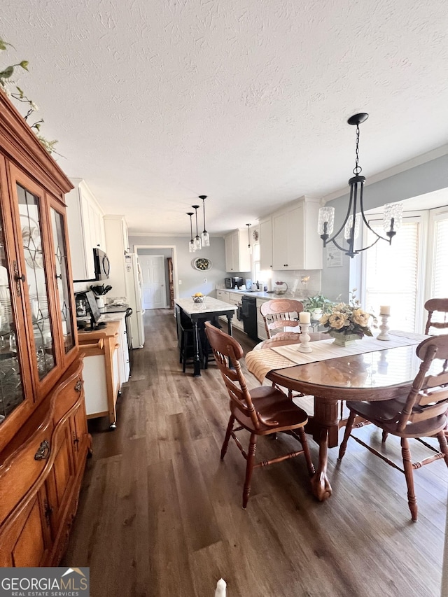 dining space featuring dark wood finished floors, a textured ceiling, a notable chandelier, and ornamental molding