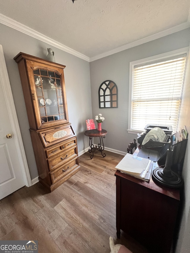 office featuring a textured ceiling, wood finished floors, baseboards, and ornamental molding