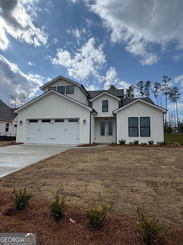 modern inspired farmhouse featuring an attached garage, board and batten siding, and driveway