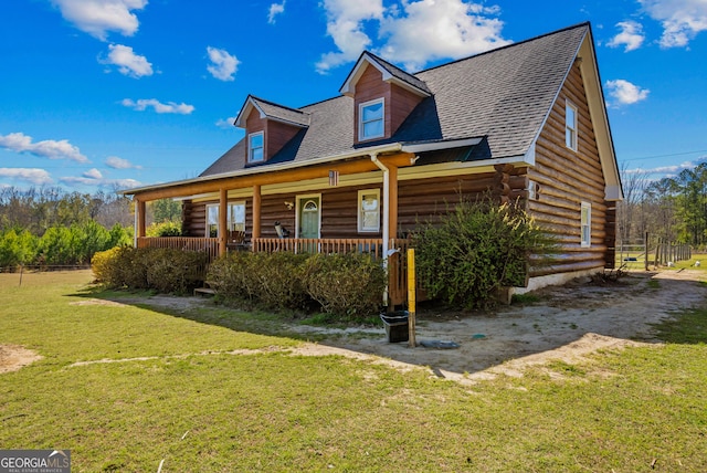 log cabin featuring a front yard, log siding, a porch, and roof with shingles