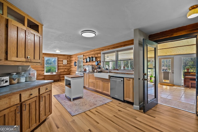 kitchen with light wood-type flooring, open shelves, a sink, rustic walls, and dishwasher