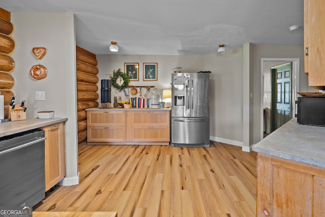 kitchen featuring light countertops, light wood-style floors, baseboards, and stainless steel appliances