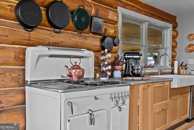 kitchen featuring a sink, gas range, and rustic walls