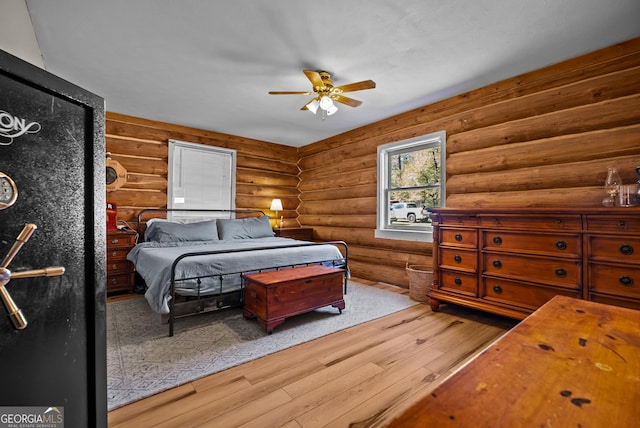 bedroom featuring a ceiling fan, wood finished floors, and rustic walls