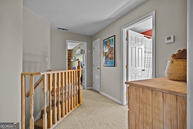 corridor featuring visible vents, an upstairs landing, light colored carpet, and baseboards