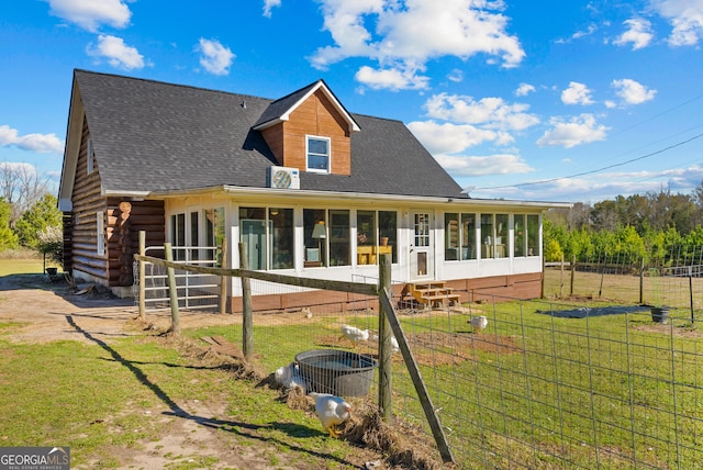 rear view of property with a sunroom, fence, a yard, a shingled roof, and log siding