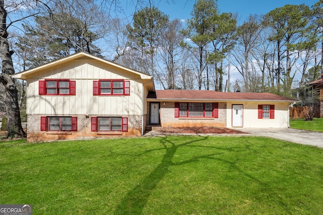 split level home featuring board and batten siding, a front yard, brick siding, and driveway