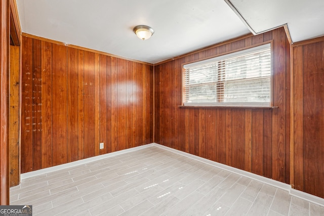 spare room featuring baseboards and wood walls