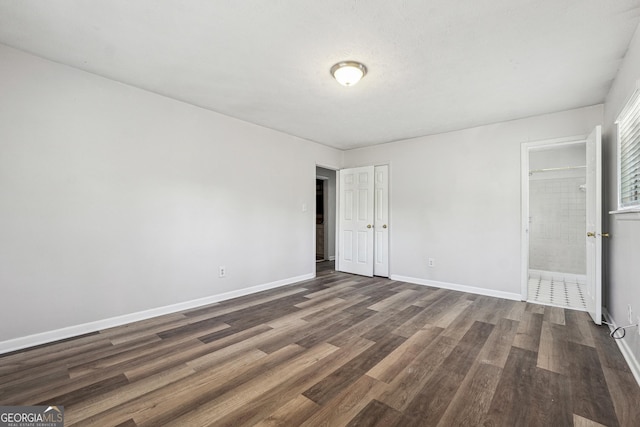 unfurnished bedroom with dark wood-style floors and baseboards