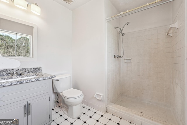 full bathroom featuring visible vents, toilet, a tile shower, baseboards, and vanity