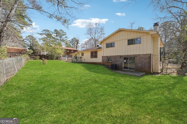 back of house featuring a lawn, a fenced backyard, brick siding, central AC unit, and a chimney