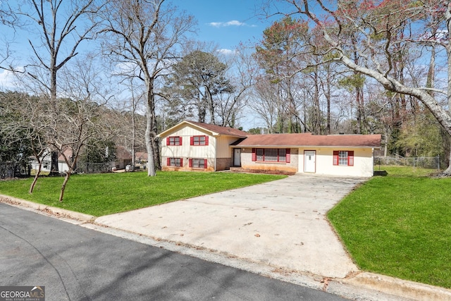 split level home with a front lawn, fence, brick siding, and driveway