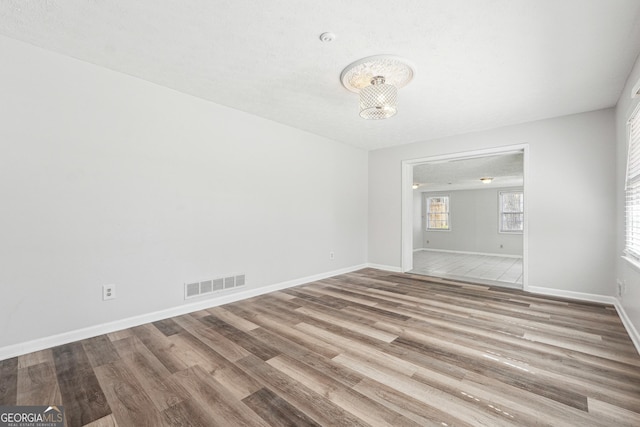 unfurnished room featuring wood finished floors, visible vents, and baseboards