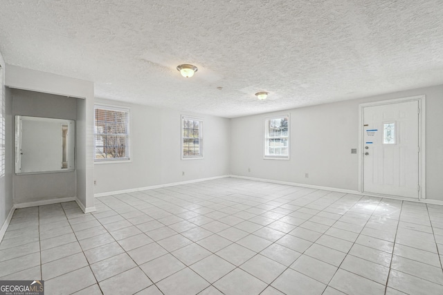 unfurnished living room with light tile patterned floors, baseboards, and a textured ceiling