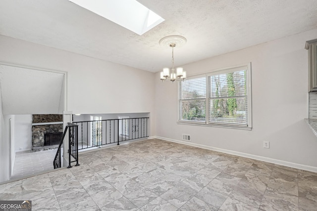 empty room featuring visible vents, a textured ceiling, an inviting chandelier, a fireplace, and baseboards