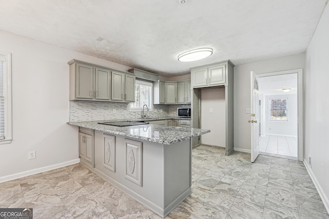 kitchen featuring light stone countertops, a peninsula, gray cabinets, marble finish floor, and backsplash