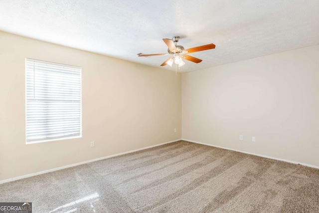 spare room featuring a textured ceiling, carpet, baseboards, and ceiling fan