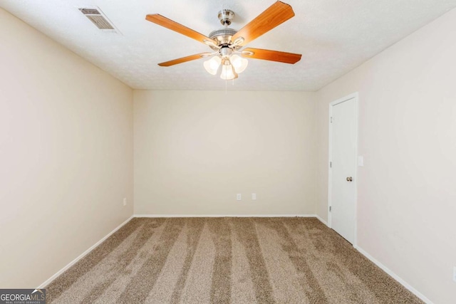 carpeted empty room featuring visible vents, baseboards, and a ceiling fan