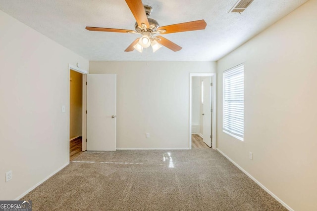 unfurnished bedroom featuring a ceiling fan, visible vents, baseboards, carpet floors, and a textured ceiling