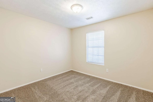 unfurnished room with visible vents, carpet flooring, a textured ceiling, and baseboards