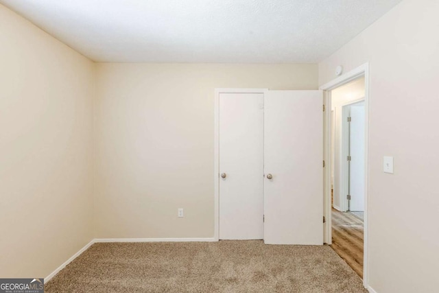 unfurnished bedroom featuring baseboards and light colored carpet