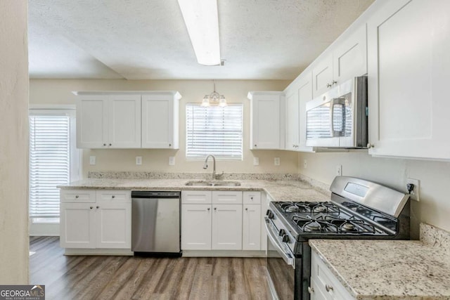 kitchen featuring white cabinetry, stainless steel appliances, light wood-type flooring, and a sink