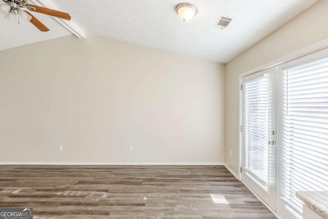 unfurnished room with a ceiling fan, wood finished floors, baseboards, visible vents, and lofted ceiling with beams