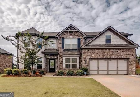 craftsman house featuring a front yard, an attached garage, brick siding, and driveway