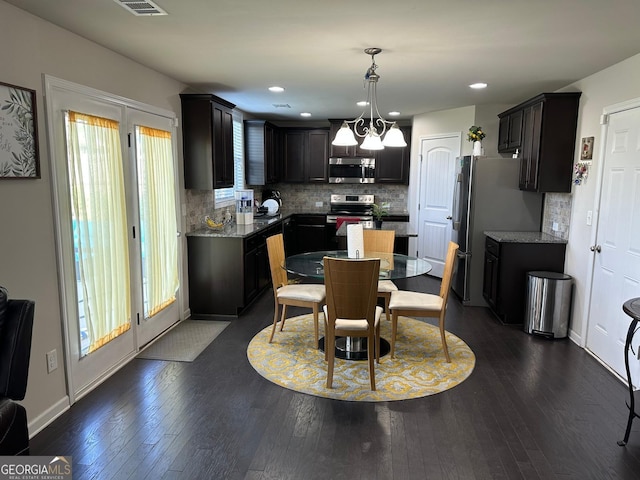 kitchen with tasteful backsplash, appliances with stainless steel finishes, dark cabinets, and dark wood-style flooring