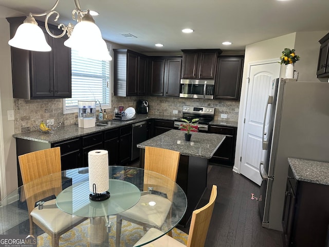 kitchen featuring visible vents, dark wood-type flooring, stone countertops, a kitchen island, and appliances with stainless steel finishes