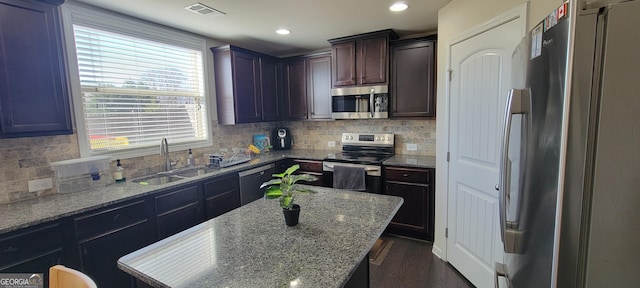 kitchen with tasteful backsplash, visible vents, light stone countertops, stainless steel appliances, and dark wood-style flooring