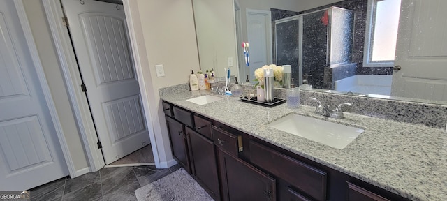 bathroom with a shower stall, double vanity, baseboards, and a sink