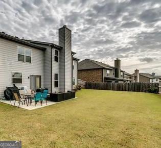 back of property with a patio, a yard, and a chimney