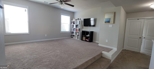 unfurnished living room with visible vents, a ceiling fan, baseboards, and carpet floors