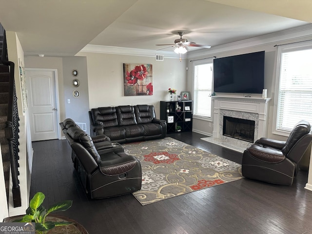 living room featuring a high end fireplace, visible vents, wood finished floors, and ornamental molding