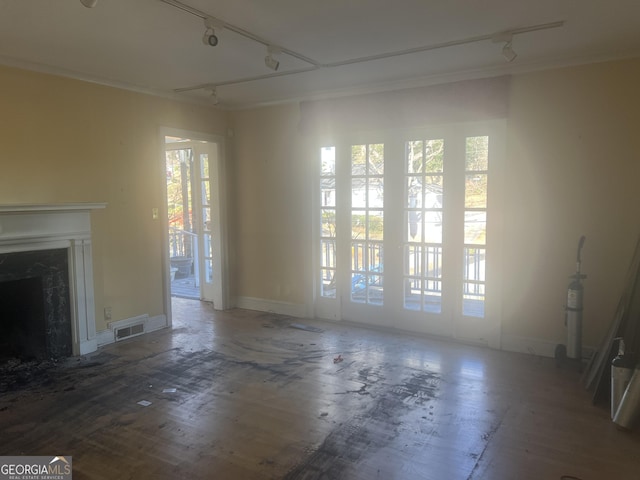 unfurnished living room featuring rail lighting, a fireplace, visible vents, and ornamental molding