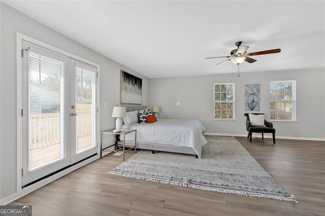 bedroom featuring access to exterior, wood finished floors, baseboards, and french doors