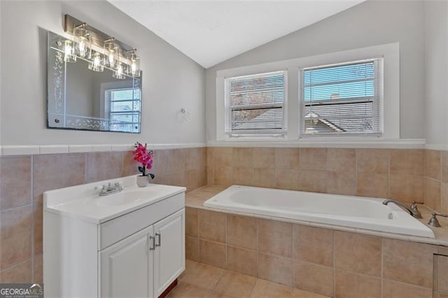 full bath with tile walls, tile patterned flooring, lofted ceiling, a bath, and vanity