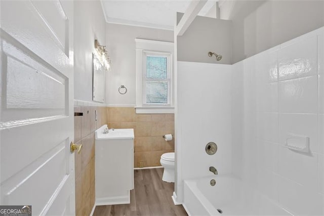 bathroom with toilet, shower / tub combination, vanity, wood finished floors, and tile walls