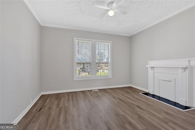 unfurnished living room featuring ornamental molding, a ceiling fan, a textured ceiling, wood finished floors, and baseboards